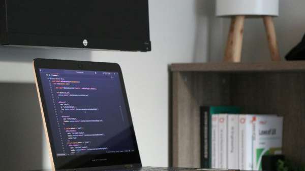 A laptop displaying code in a blue-lit workspace.